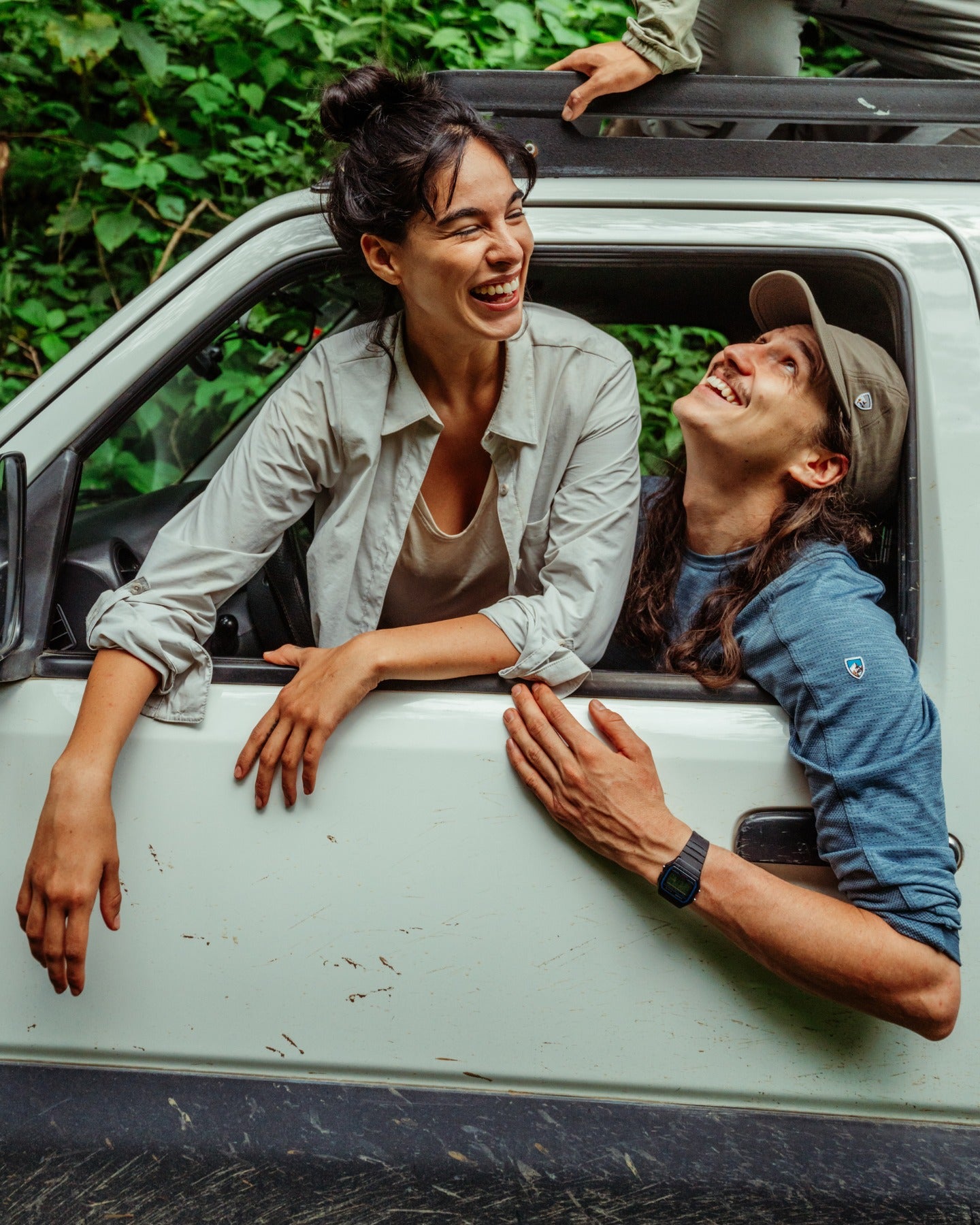 Two people leaning out of a car window with a green forest background photo by Kuhl