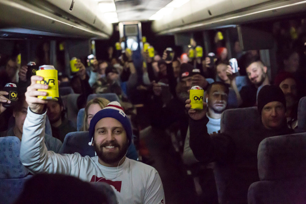 People on a train holding yellow cans with OvrRide branding