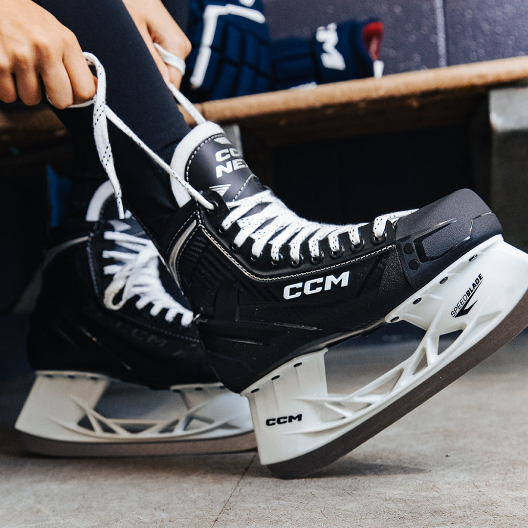 Close-up of black CCM hockey skates with white laces on a concrete surface. photo by ccm