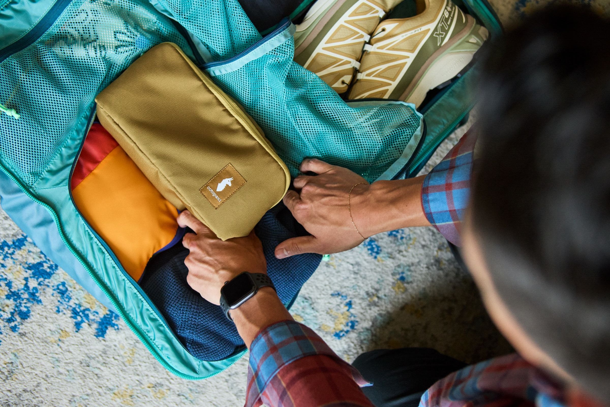 Person packing for a trip in a cotopaxi pack Photo by Cotopaxi
