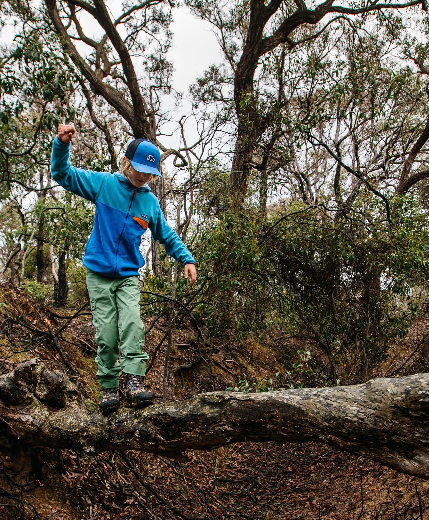 Boy balancing on a log in a forest photo by Patagonia