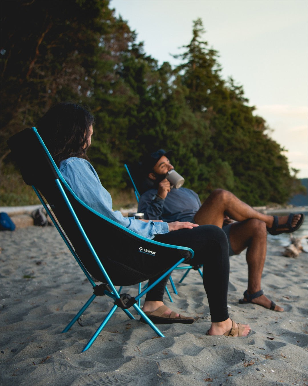 Two people sitting at beach  on chairs in a forested area photo by helinox