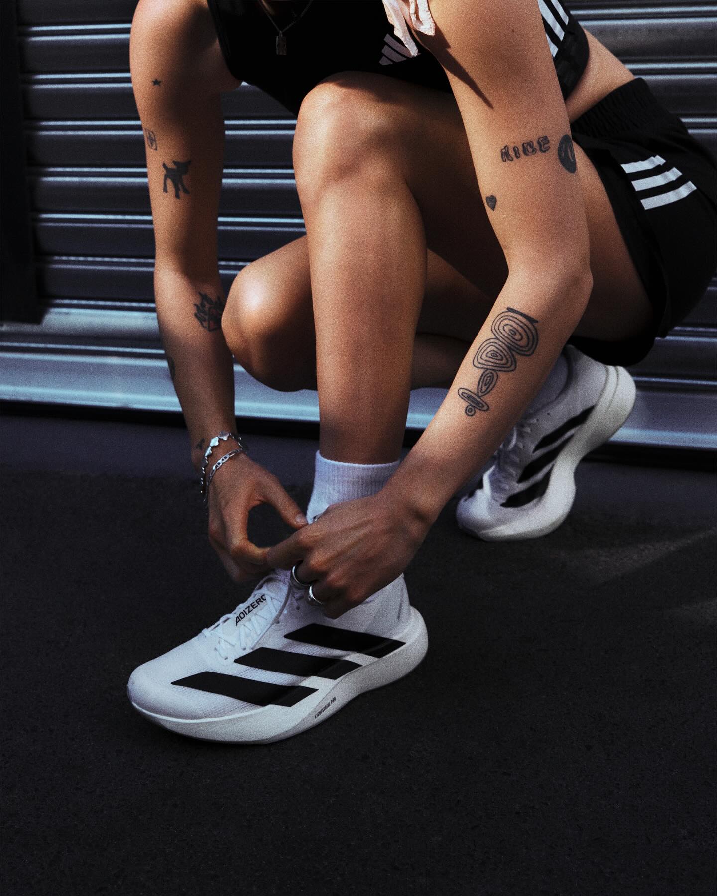 Person wearing Adidas shoes tying shoelaces on a dark background photo by adidas