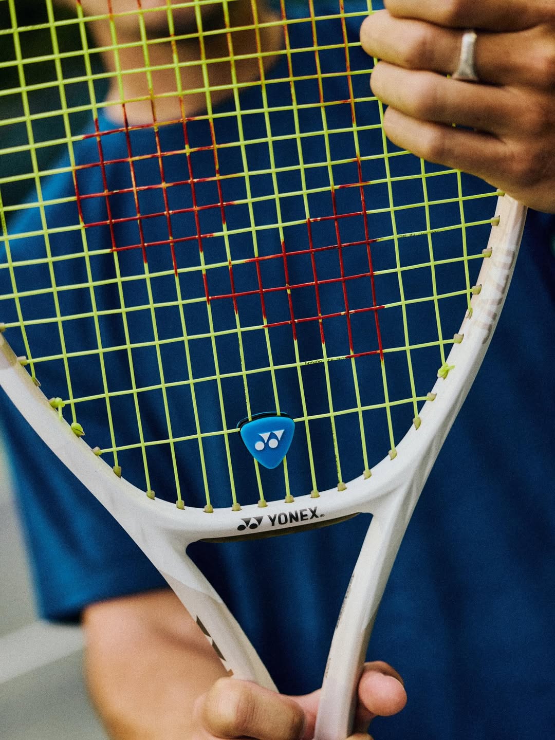 Close-up of a tennis racket with Yonex branding held by a person.