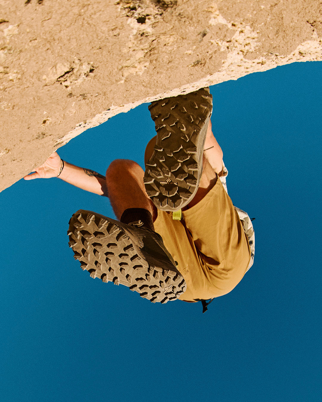 Person wearing brown boots stepping into a pool of water with a blue background