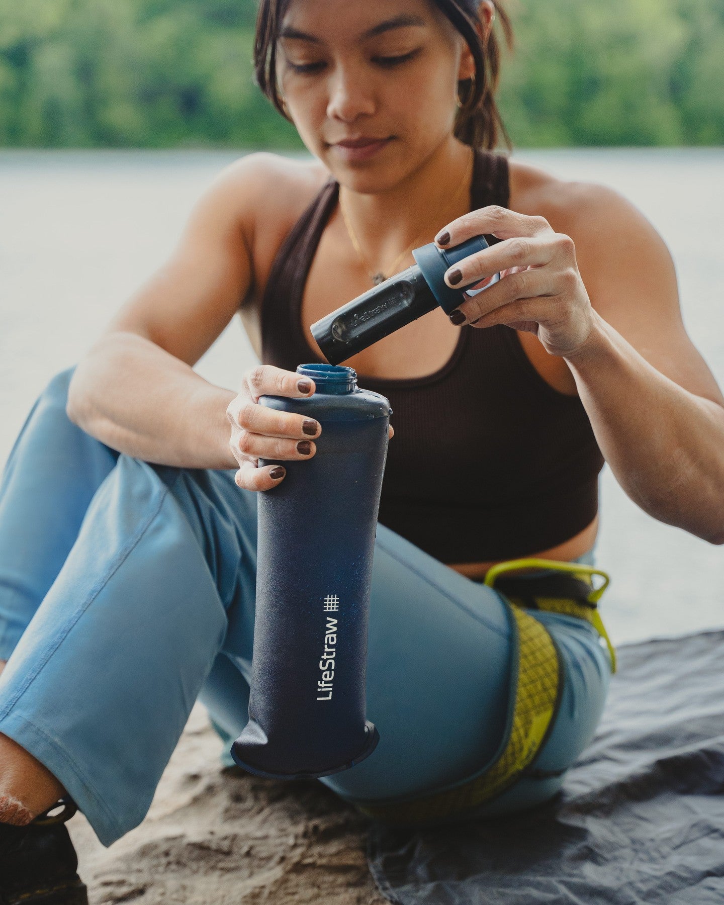 Person using a LifeStraw water filter by a body of water photo by LifeStraw
