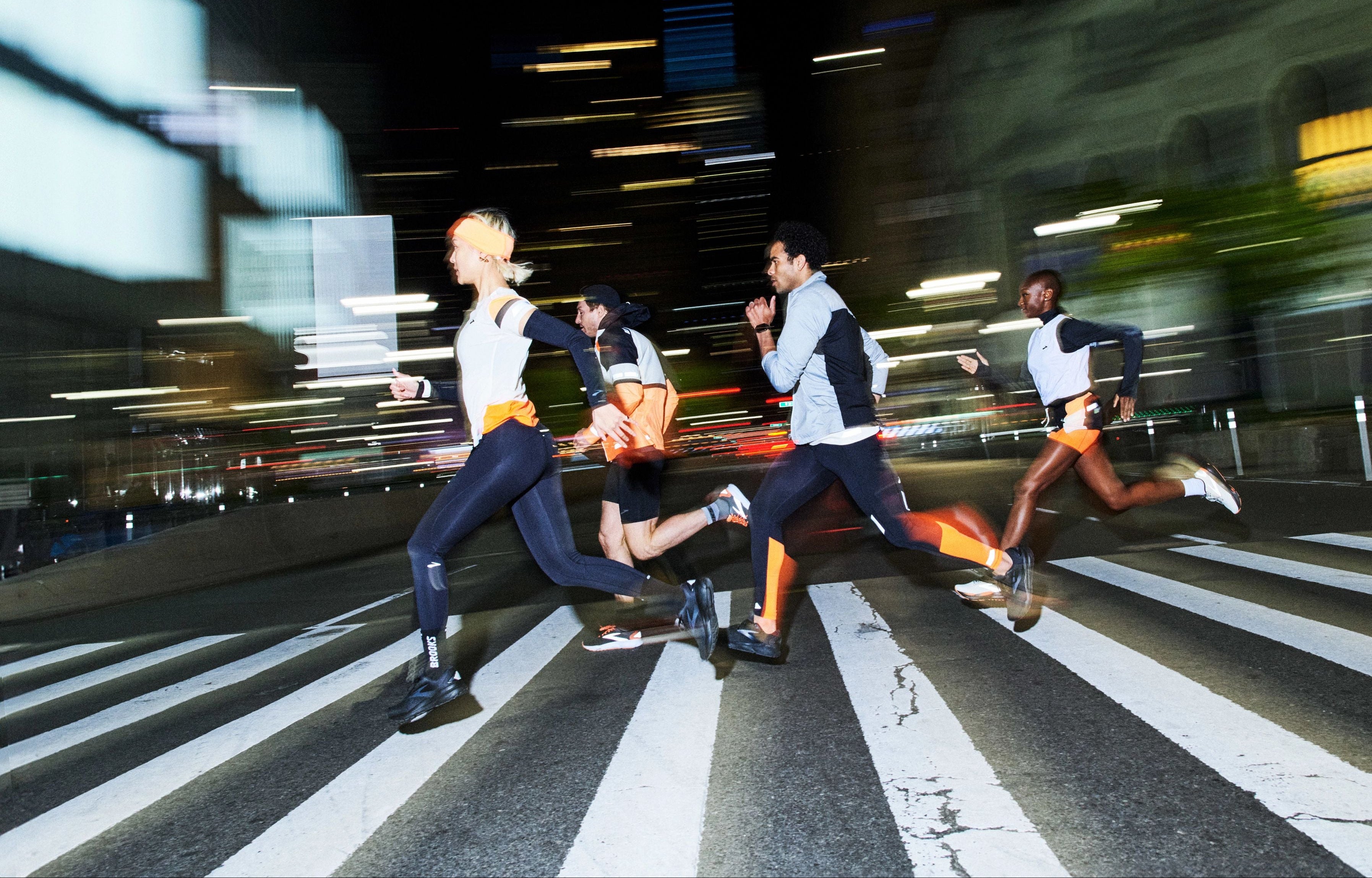 Runners crossing the streets of NYC at night Photo by Brooks