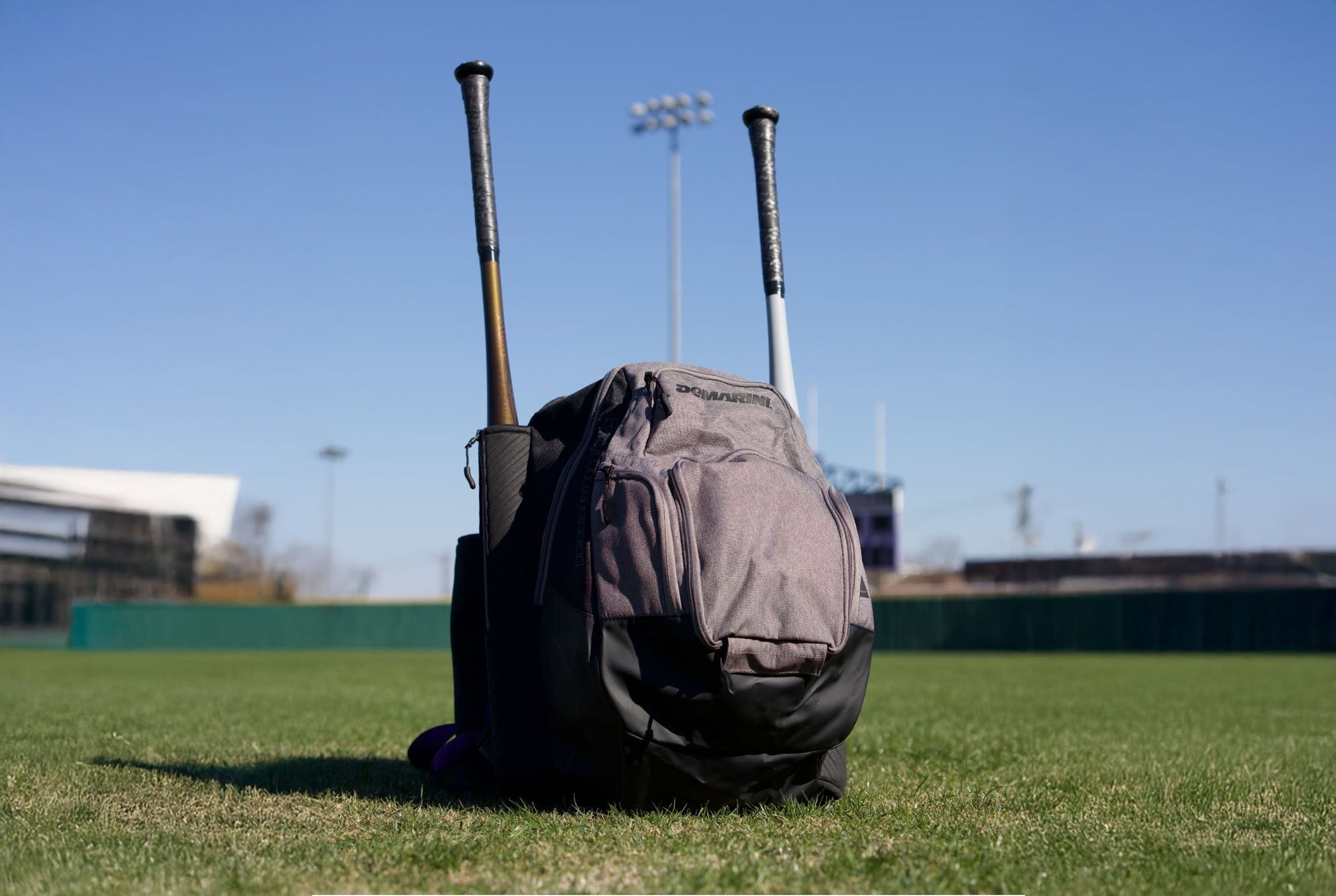 Backpack with baseball bats on a grass field photo by demarini